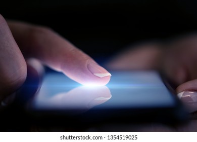 Finger touching phone with dark background with copyspace