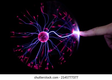 Finger touching plasma light ball on black background