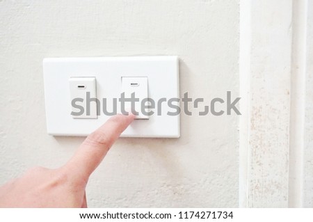 Finger trying to turnoff switch of the lamp at the wall