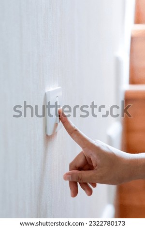Finger turning off or turning on on lighting switch at home with wooden step background. Power, Energy, Saving Electrical concept, close up.