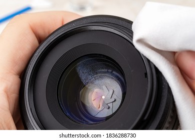 Fingerprint On A Front Camera Lens Close-up. Hands Wiping A Lens Rim With A Microfiber Cloth Before Cleaning The Greasy Stain On A Lens. Maintenance Of Photographic Equipment. Top View.