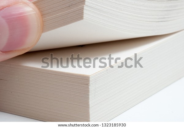Fingers folding book pages. Hand turning book\
pages on the blank background. Thumb dividing the book pages into 2\
parts.