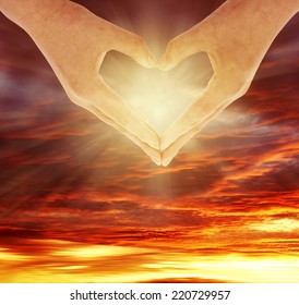 Fingers forming heart shape in front of sky - Shutterstock ID 220729957