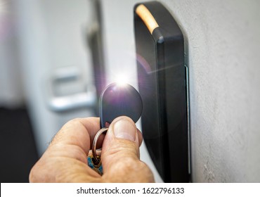 Fingers holding key fob on key fob sensor with door handle out of focus in the distance. Bright flash was added to the key fob for dramatic effect