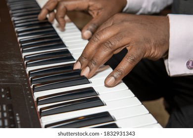 Fingers Of An Old African American Man Playing A Keyboard Piano Wearing A Black Suit And Pink Shirt