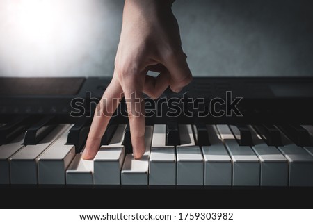 fingers press piano keys close-up, hand of a composer or musician plays a synthesizer