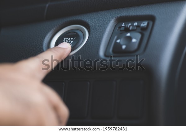 Fingers are pressing the car start button. Young man\
starting to drive a\
car.
