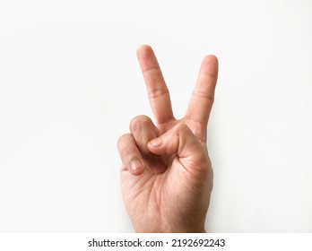 Fingers Of The Right Hand Forming A Peace Symbol By Holding Two Fingers Up On A White Background