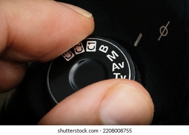 Fingers selecting manual mode on a professional camera. man putting the manual mode on the photo camera. Dial with manual mode in digital photography cameras. Man selecting manual mode