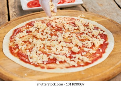 Fingers With Shredded Cheese Above Pizza Crust. Spreading Shredded Cheese.