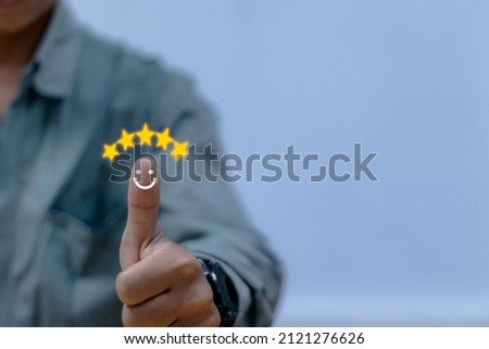 
Fingers with smiley face icon and five stars above blurred background. Customer Satisfaction and Business Acceptance Survey Concept.
