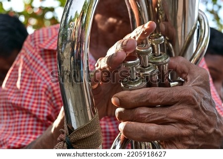 The fingers of a trumpet player are pressing the keys of the trumpet