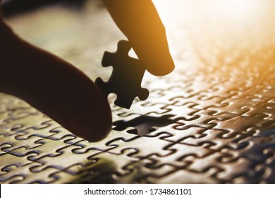 Fingers of a white man putting the last piece of a puzzle. Man building a puzzle. Metaphor and symbol of integration, teamwork, effort