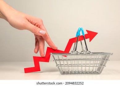 The fingers of a woman's hand step up the arrow of a chart lying on a shopping basket. Crisis and rising commodity prices concept