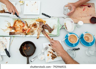 Finished Leftover Party Table Empty Of Food After Being Eaten, With Used Messy Dishes Evidence Of Being Enjoyed, Delicious Feast Concept With Hands Reaching And Holding. Top View