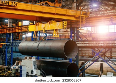 Finished pipe transportation by overhead crane in pipe factory - Shutterstock ID 2328053207