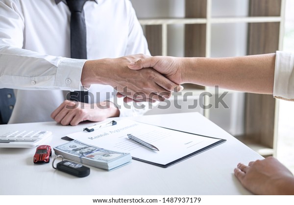 Finishing up of\
conversation, Realtor agent manager shaking hands with woman client\
after signing rental form contract agreement, renting considering\
vehicle car\
insurance.