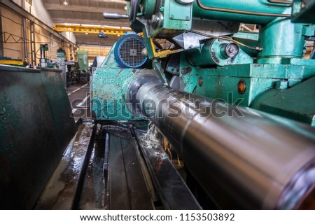 Finishing of the round part, grinding of the large shaft on the machine, at the machine-building enterprise, wide-angle photo, view from the side