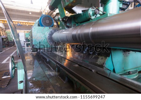 Finishing of the round part, grinding of the large shaft on the machine, at the machine-building enterprise, wide-angle photo, view from the side