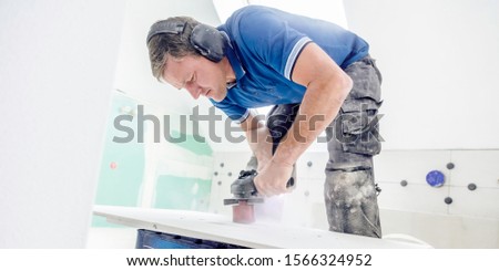 Finishing works - the tiler cuts a round hole in the tile with an angle grinder
