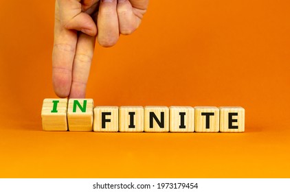 Finite or infinite symbol. Businessman turns wooden cubes and changes the word 'finite' to 'infinite'. Beautiful orange table, orange background. Business, finite or infinite concept. Copy space.