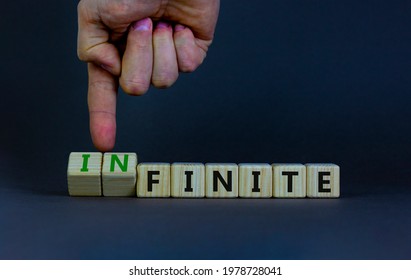 Finite or infinite symbol. Businessman turns wooden cubes and changes the word 'finite' to 'infinite'. Beautiful grey table, grey background. Business, finite or infinite concept. Copy space.