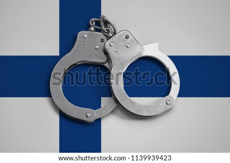 Finland flag  and police handcuffs. The concept of observance of the law in the country and protection from crime