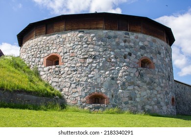 Hämeenlinna, Finland - June 24 2022: A part of the Hämeenlinna castle made with stone, looking like a face with windows depicting the eyes and mouth against a blue sky and green yard.