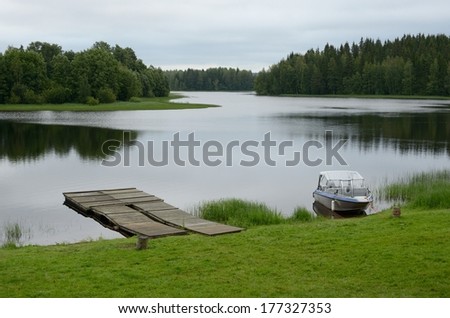 Finland river landscape with woody pier and powerboat 