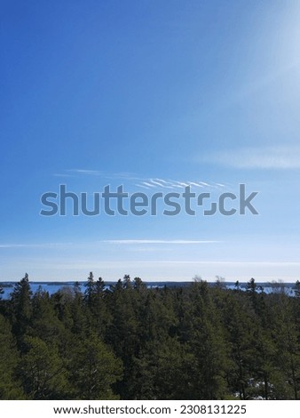 Finnish archipelago in the spring, there is still some snow on the ground. Coniferous forest, coastline, islands and bright blue sky and sea. Sun is shining and there are just a few clouds in the sky.