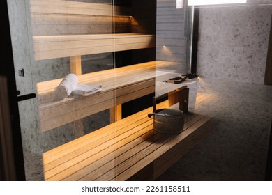 Finnish bathroom with a small wooden sauna. Modern spa interior. Photo through the glass door