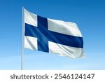 Finnish flag waving in a clear blue sky. The flag of Finland features a blue Nordic cross on a white background. Finnish flag symbolizing Finland