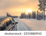 Finnish Lapland in winter. Empty highway in northern forest. Lots of snow. Sunset with reflection in glossy parts of car