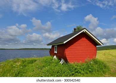 Finnish Sauna On The Shore Of The Blue Lake Summer Day. Northern Finland, Lapland