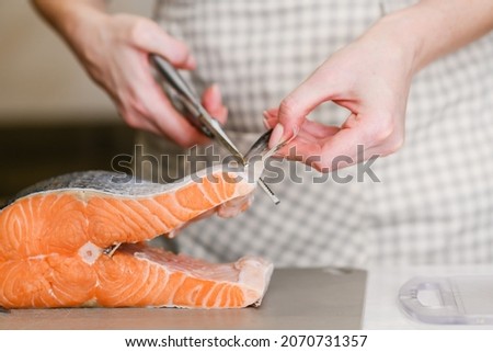 Fins of a red fish removed with fish shears on the chopping board. Butchering salmon, piece of salmon red fish meat.