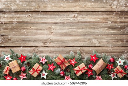 Fir Tree Branches With Advent Calendar Stars And Gift Boxes On Old Wooden Board