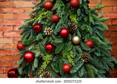 Fir tree decorated with christmas balls over red brick wall . Close-up view of beautiful christmas tree with colorful baubles and illuminated garland. Sparkling and fairy background. New year holiday - Powered by Shutterstock