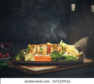 Firangi Special Sizzler Made With Panner & Fresh Veggies In A Wooden Tray . Photo Has Taken In A Dark Room With Yellow Light On A Dish .