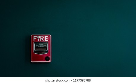 Fire Alarm On Dark Green Concrete Wall. Warning And Security System. Emergency Equipment For Safety Alert. Red Box Of Fire Alarm On Wall Of School, Hospital, Factory, Office, Apartment, Or Home.