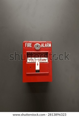 Fire alarm pull station on a wall, red emergency device with warning labels, concept of building safety and fire protection.