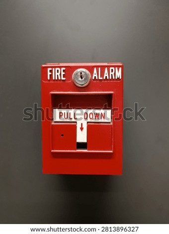 Fire alarm pull station on a wall, red emergency device with warning labels, concept of building safety and fire protection.
