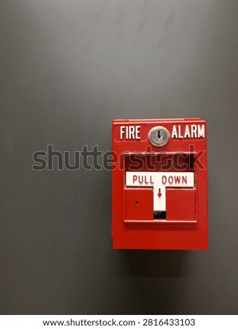 Fire alarm pull station on a wall, red emergency device with warning labels, concept of building safety and fire protection.