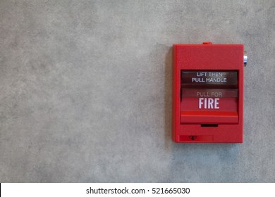 Fire alarm system in red color on grey wall.