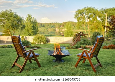 Fire in barbecue and two empty lounge chairs on backyard - Powered by Shutterstock