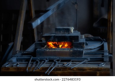 The fire of a blacksmith's forge in a brick kiln. Blacksmith tools lying next to the blacksmith's furnace. - Powered by Shutterstock