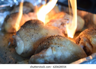 Fire Burning On Raw Chicken Thighs In A Baking Tray With Tin Foil