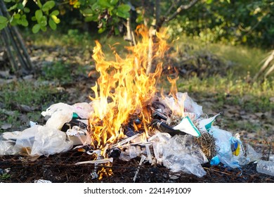 Fire burning pile of garbage. Concept, Incineration of household waste, paper, cardboard, food scraps, plastic, twigs and other waste that causes air pollution. Trash management                        - Shutterstock ID 2241491009
