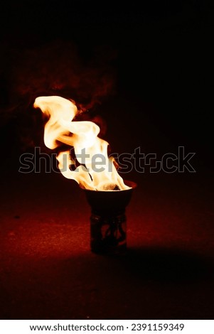fire burns in bowl, tool for fireshow, red and yellow flames, nightlife entertainment concept, vertical photo