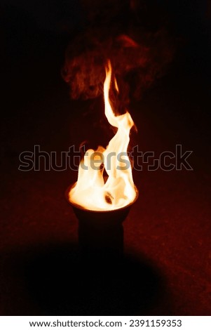 fire burns in bowl, tool for fireshow, red and yellow flames, nightlife entertainment concept, vertical photo