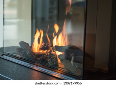 a fire burns in a glass fireplace, radiates heat - Shutterstock ID 1309199956